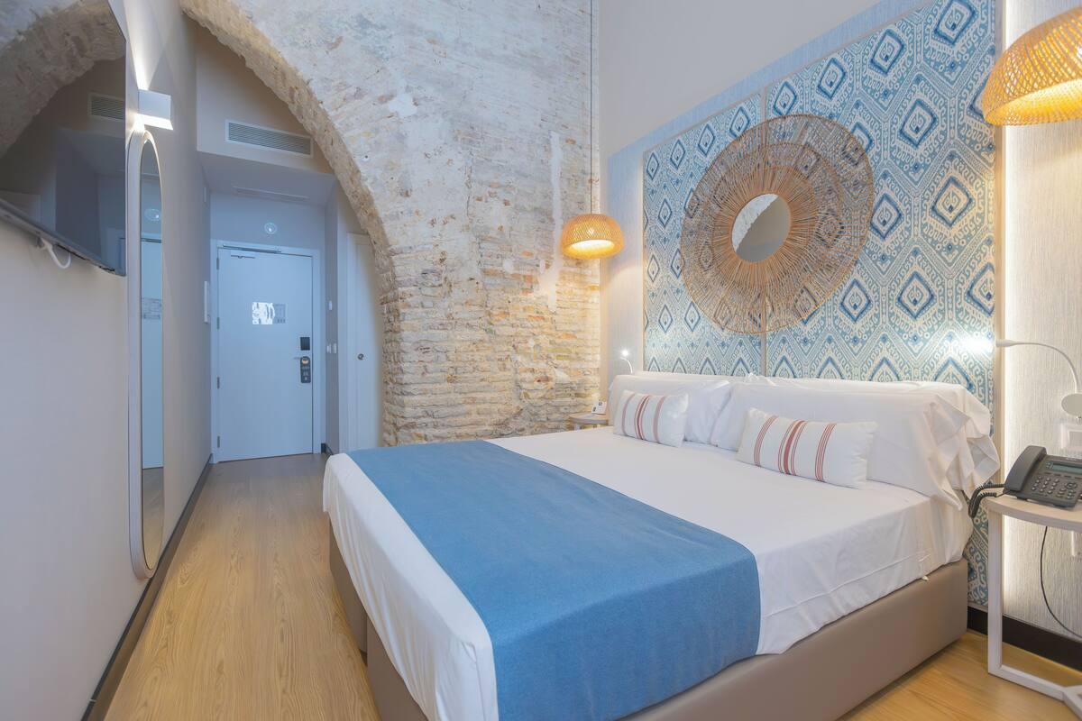 Ein Schlafzimmer mit einem großen Bett, einer Wand mit Muster, einer Steinwand und einem Holzboden.