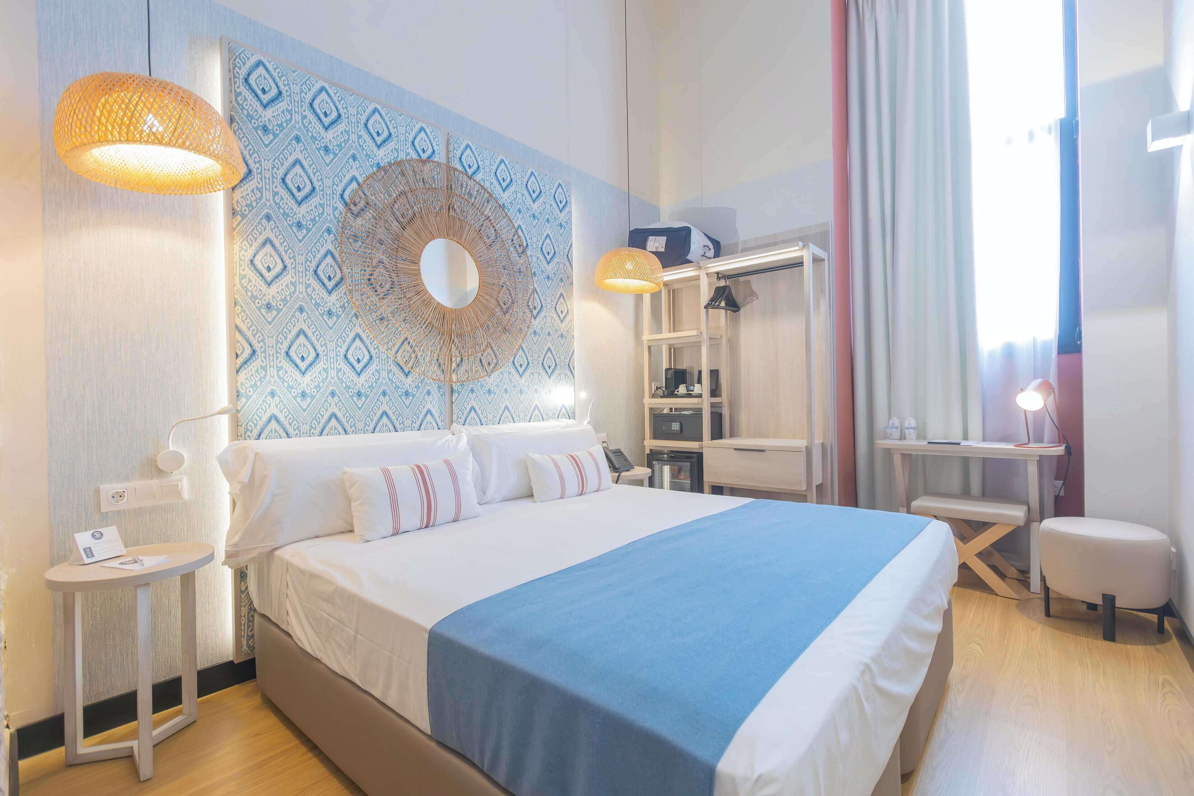 A hotel room with a large bed, bedside tables, a desk, and a wardrobe.