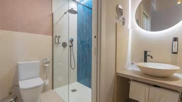 A modern bathroom with a toilet, a glass-enclosed shower, a sink, and a mirror.
