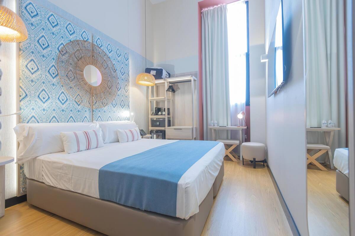 Ein modernes Hotelzimmer mit einem großen Bett, einem Schreibtisch und einem Kleiderschrank.