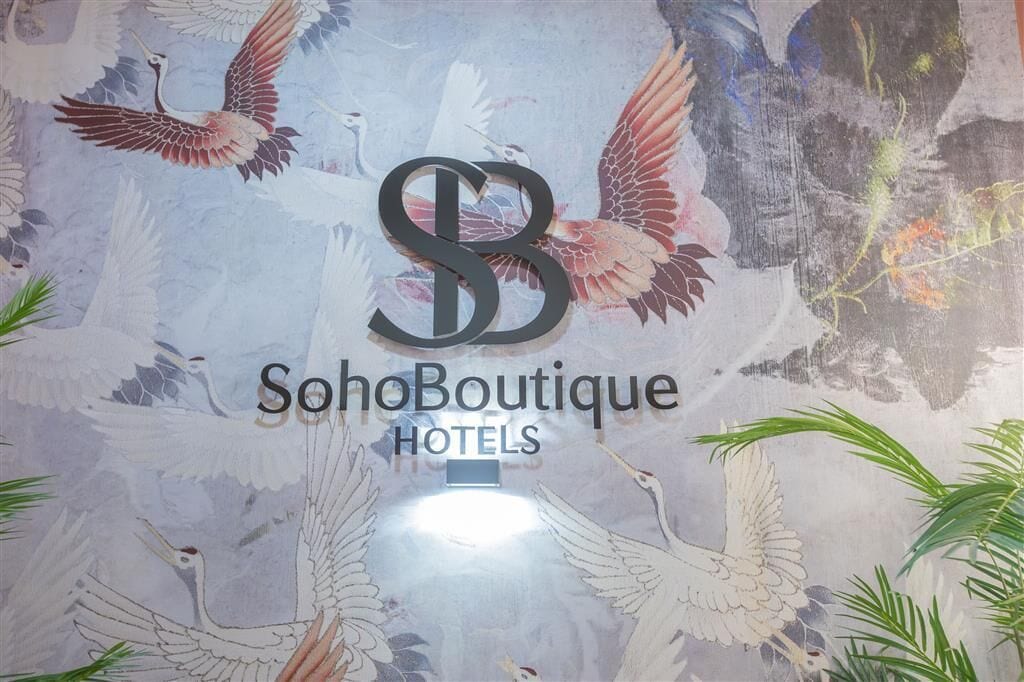 Una pared con el logotipo de SohoBoutique Hotels rodeada por un mural de aves.