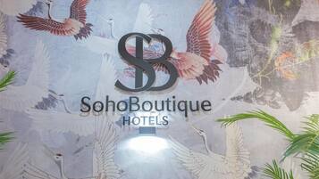 Una pared con el logotipo de SohoBoutique Hotels rodeada por un mural de aves.