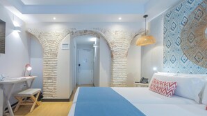 Un dormitorio con cama, escritorio y silla. Se ve una puerta que da a otra habitación.
