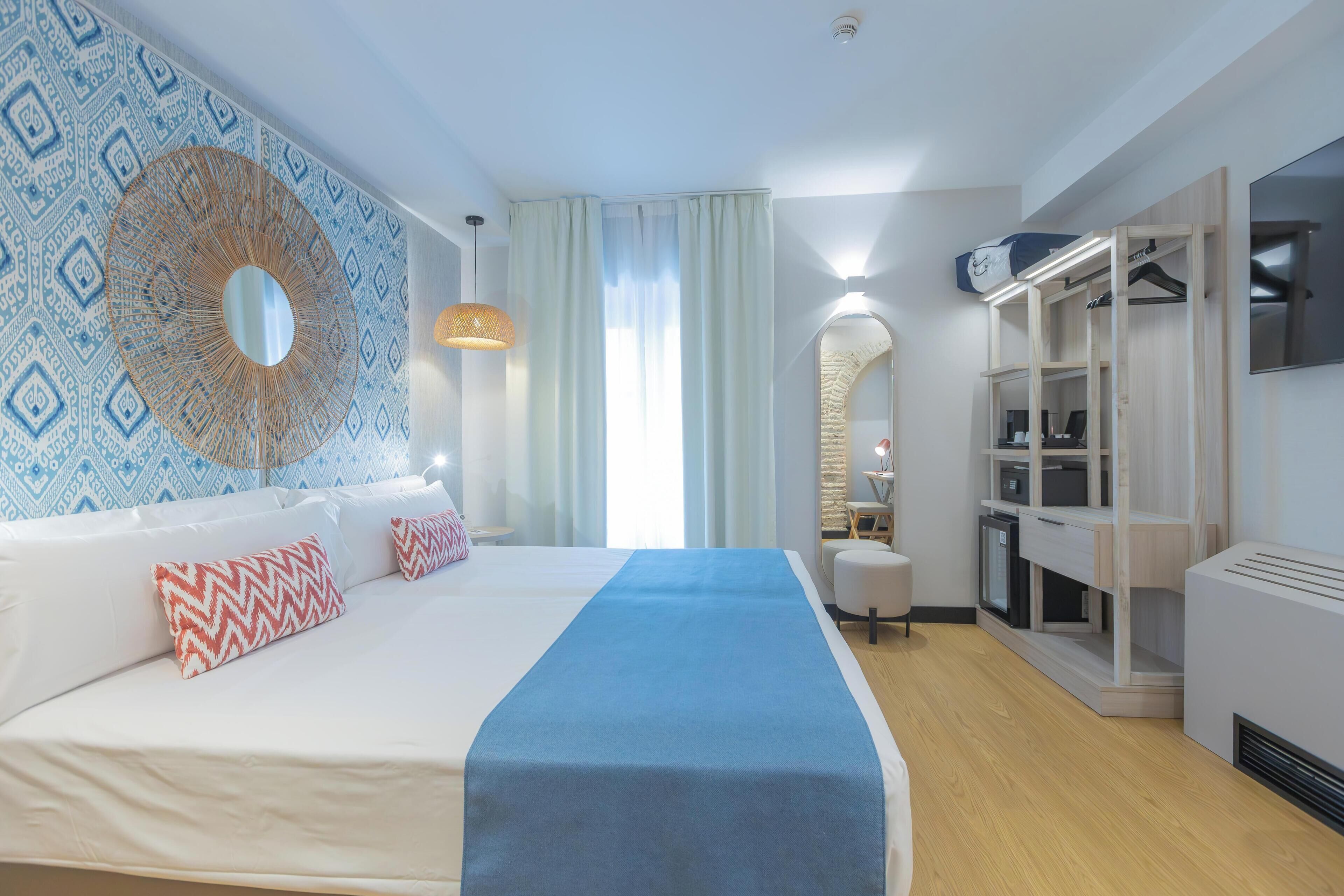 Habitación de hotel con una cama grande, un armario, un espejo y una pared con diseño geométrico.