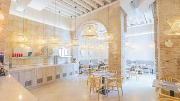 Una cafetería moderna con pared de piedra rústica, mobiliario de madera e iluminación colgante.