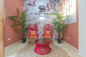 A lobby with two red chairs, a glass coffee table, and potted plants.