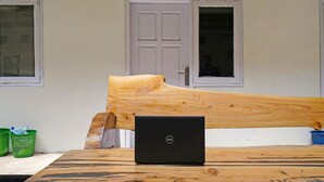 Una mesa de madera con un ordenador portátil encima, un banco de madera y una puerta al fondo.