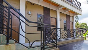 Un edificio de varios pisos con un balcón, una escalera con barandilla de metal y una puerta con ventana.