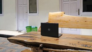 Un banco de madera con una computadora portátil, una puerta y una ventana al fondo.