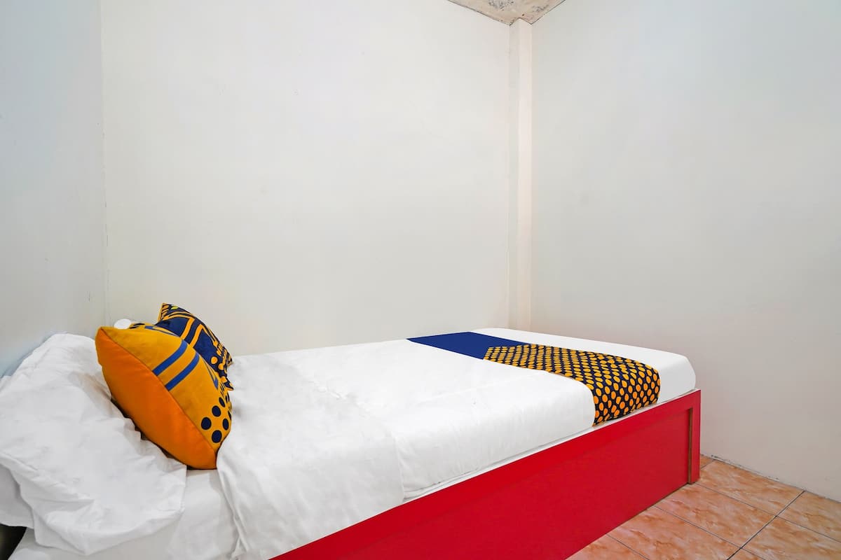 Ein kleines Zimmer mit einem Einzelbett, rotem Gestell und weißer Bettwäsche.