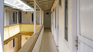 Un pasillo con puertas a ambos lados, suelo de baldosas y estructura de techo metálica.