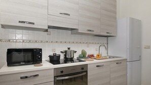 A modern kitchen with a microwave, oven, sink, and white cabinets. - Porto Letizia Torino 2B, Porlezza, Italy (Porlezza)