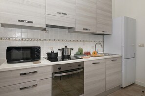A modern kitchen with a microwave, oven, sink, and white cabinets.