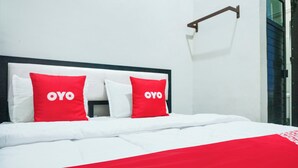 Una cama con ropa de cama blanca y dos almohadas rojas con la palabra "OYO".