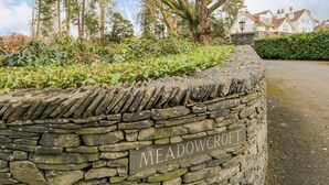 Eine Steinmauer mit einem Schild, auf dem 'MEADOWCROFT' steht.