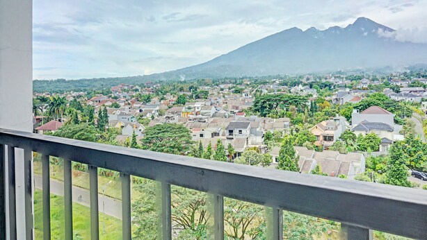 A balcony with a view of a town and a mountain. - Hotel O Skyland Bogorienze Apartment (Bogor)