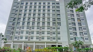 A multi-story building with a central entrance, balconies, and a sign indicating a marketing office. - Hotel O Skyland Bogorienze Apartment (Bogor)