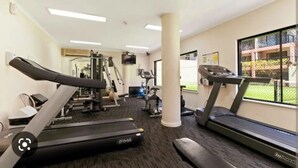 Un gimnasio con cintas de correr, máquinas de pesas y una pantalla de televisión.
