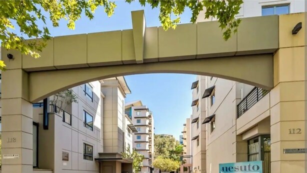 Un edificio moderno con un acceso destacado bajo un arco.