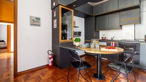 A modern kitchen with a dining area, a fire extinguisher, and a sign indicating fresh milk. - GuestHost - Spacious two-room apartment with kitchen for 5 persons with one bedroom, living room with sofa bed and a loft (overlooking the rooms below) with a bed and office area. The kitchen/dining room is separate. In total 65 sqm in old Milan building (Milan)