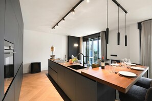 Una cucina moderna con isola centrale, lavello incassato e illuminazione a sospensione.