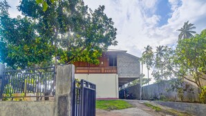 A gated residential area with a concrete pathway leading to a building with a flat roof and a balcony. - Hotel O Sosonopan Homestay Near LANTAMAL VIII MANADO (Manado)