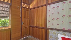 A wooden room with a large window, a door, and a bed with a red pillow labeled "OYO". - Hotel O Sosonopan Homestay Near LANTAMAL VIII MANADO (Manado)