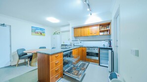 A compact kitchen with wooden cabinets, a built-in microwave, a stove, and a dishwasher. - Luxurious oasis 10mins to Perth DT, Elizabeth Quay & PCEC (Perth)