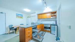Une cuisine compacte avec des meubles en bois, un four à micro-ondes encastré, une cuisiniÚre et un lave-vaisselle.