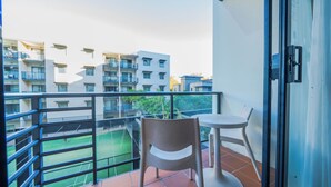 A balcony with a table and chair, a tennis court in the background, and multi-story residential buildings. - Luxurious oasis 10mins to Perth DT, Elizabeth Quay & PCEC (Perth)
