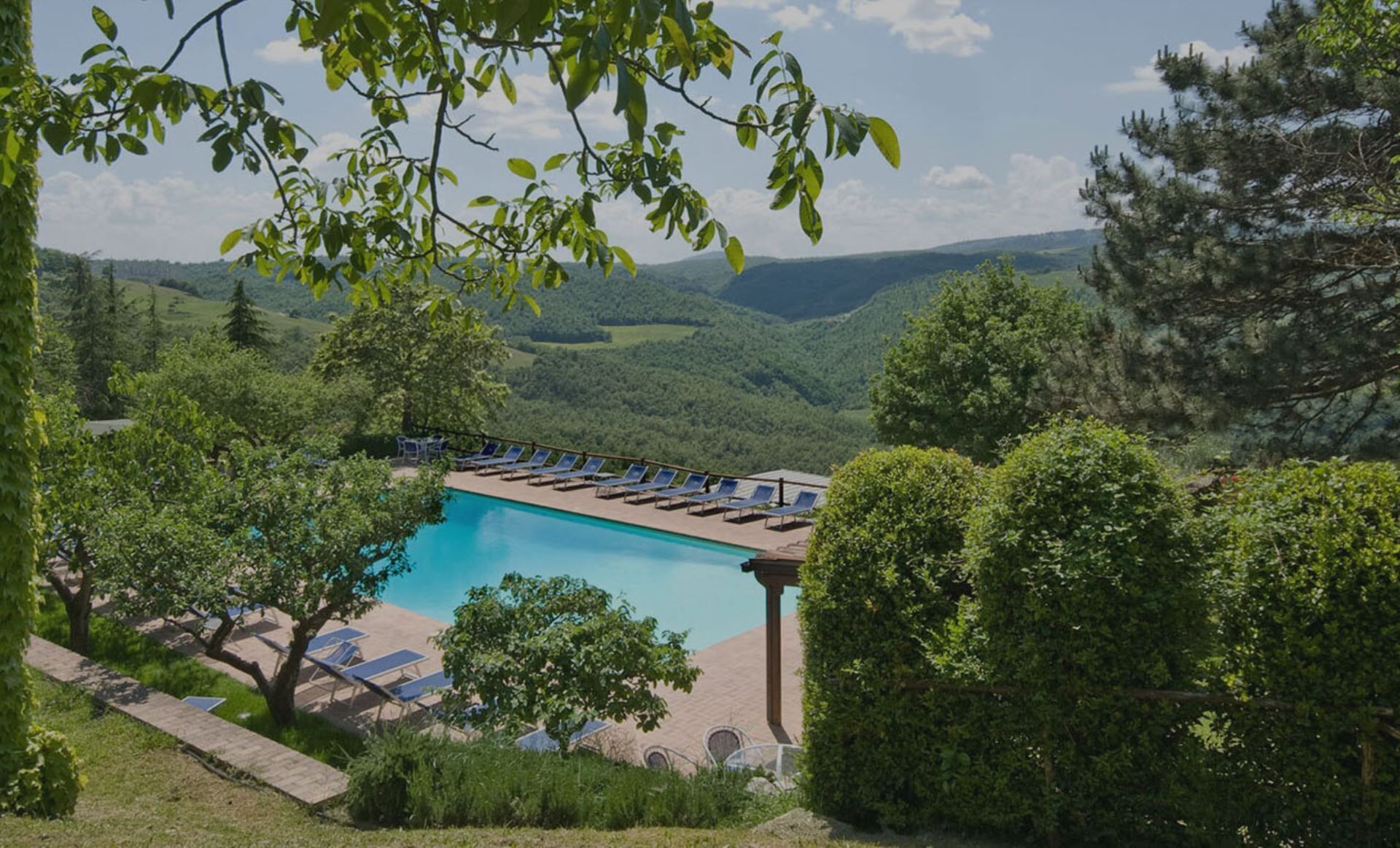 A pool with lounge chairs and a view of the surrounding landscape.