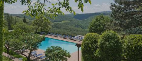 A pool with lounge chairs and a view of the surrounding landscape.