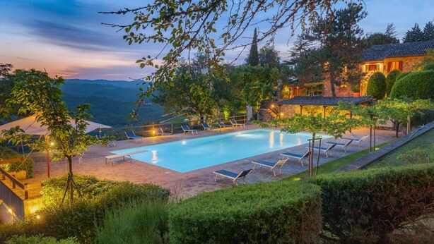 Area piscina con lettini e vista sulle montagne al crepuscolo.