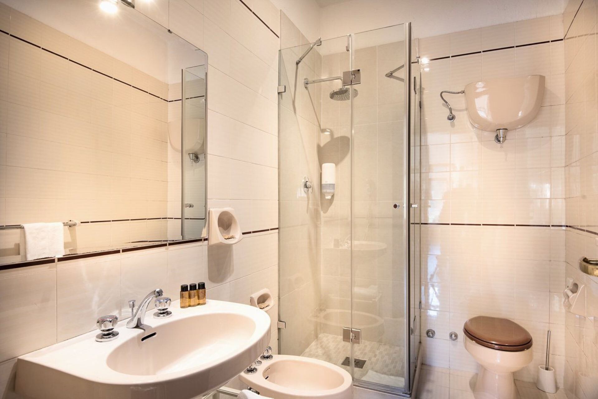 A modern bathroom with a glass-enclosed shower, a sink with toiletries, and a toilet.
