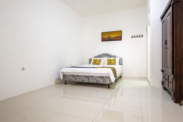 A bedroom with a bed, a painting on the wall, and a wooden wardrobe. - SPOT ON 3961 Fico's Residence Syariah (Bekasi)