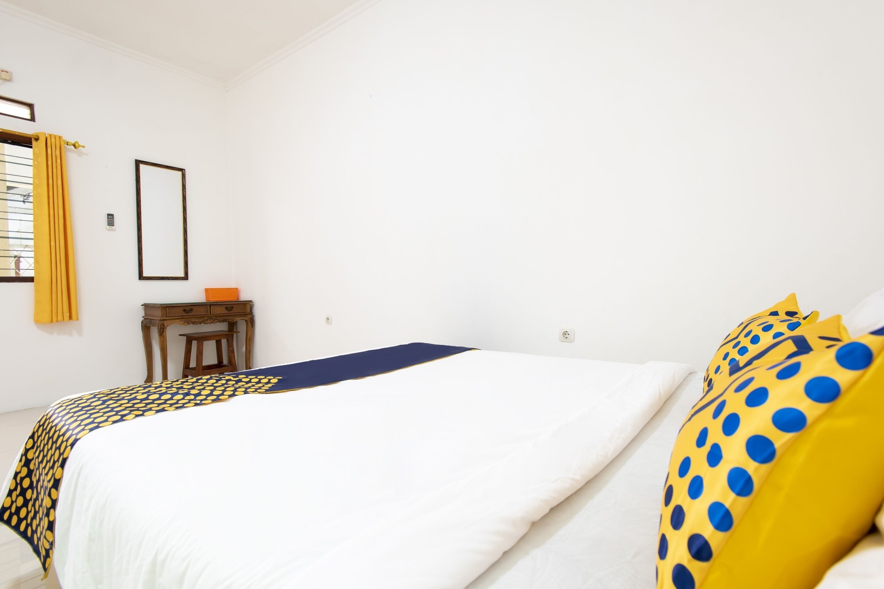 A bedroom with a bed, a nightstand, and a window with curtains.