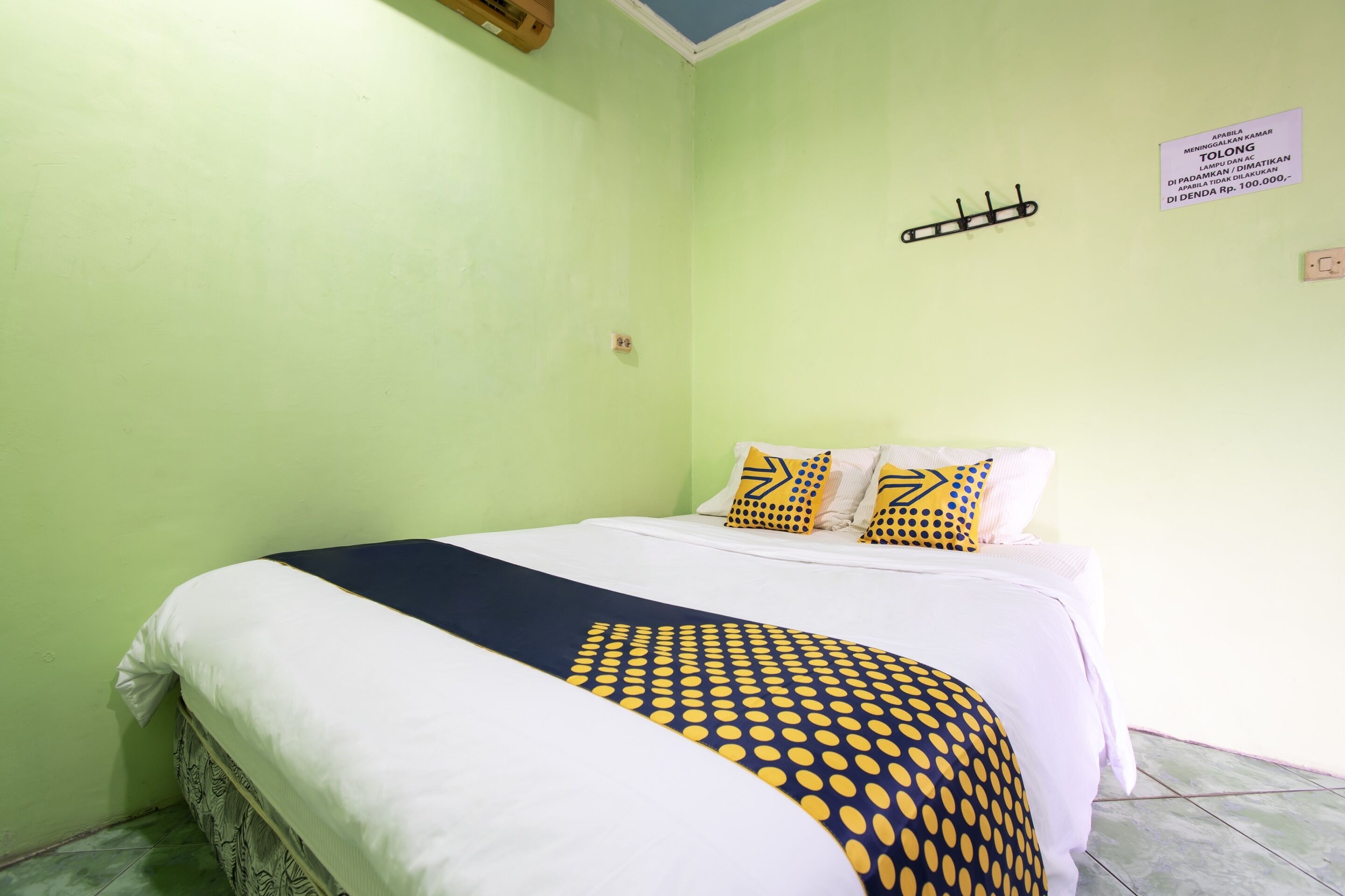 Um quarto com uma cama, paredes verdes e uma placa na parede.