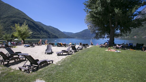 A lakeside beach with lounge chairs and a grassy area. - Porto Letizia Venezia 8, Porlezza, Italy (Porlezza)