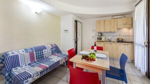 A compact living space with a kitchenette, a dining area with a table and chairs, and a sofa. - Porto Letizia Venezia 8, Porlezza, Italy (Porlezza)