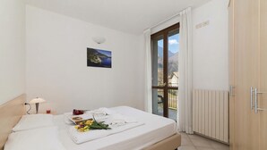 A hotel room with a bed, a nightstand, a lamp, a picture on the wall, and a view of the outdoors. - Porto Letizia Tchaikovsky 7, Porlezza, Italy (Porlezza)