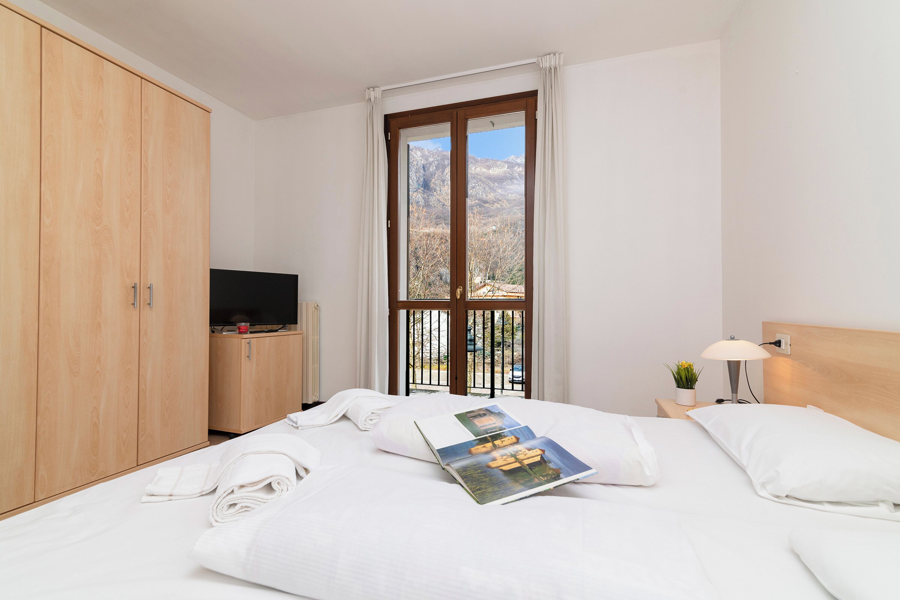 Ett hotellrum med en säng, en tv, ett fönster med utsikt och en garderob i trä.