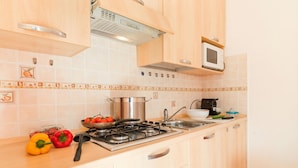 A kitchen with wooden cabinets, a gas stove, a microwave, and a tiled backsplash. - Porto Letizia Napoli 7, Porlezza, Italy (Porlezza)