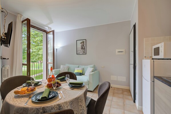 A dining area with a table set for four, a sofa, and a kitchen with a microwave.