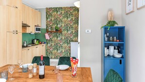 Une cuisine compacte avec des meubles en bois, un four à micro-ondes et un dosseret de crédence recouvert de carreaux verts.