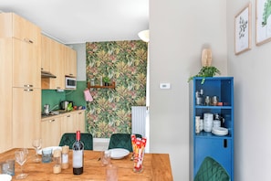 A compact kitchen with wooden cabinets, a microwave, and a green-tiled backsplash.