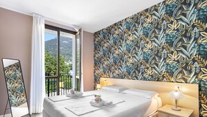 Une chambre d’hôtel avec un grand lit, une table de chevet avec une lampe, un miroir et une vue sur l’extérieur.