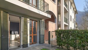 A multi-story residential building with balconies, sliding glass doors, and a well-maintained lawn. - Porto Letizia Ferrara 1, Porlezza, Italy (Porlezza)