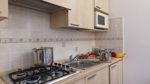 A kitchen with a gas stove, stainless steel sink, and a microwave. - Porto Letizia Como 3, Porlezza, Italy (Porlezza)