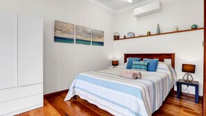 Een slaapkamer met een bed, nachtkastjes, een kledingkast en kunstwerken aan de muur.