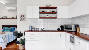 A modern kitchen with white cabinets, a wooden countertop, and a built-in oven.